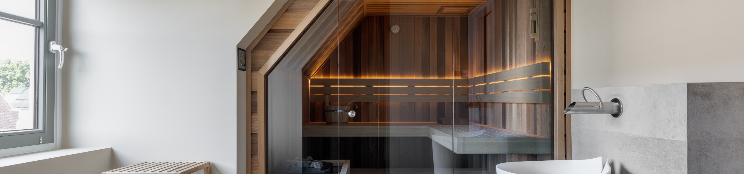 Maatwerk sauna red cedar in exclusieve badkamer met gestucte wanden saunabanken met verlichting achter de rugleuning en een finse kachel